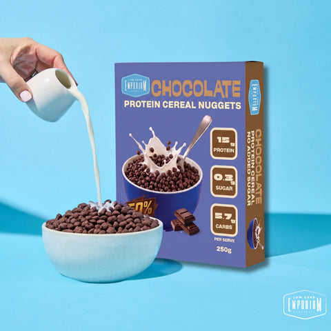 Milk being poured over a bowl of chocolate protein cereal nuggets beside the box